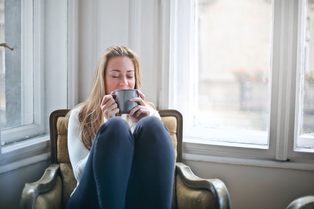 woman sitting in a chair with her legs up and holding a cup in her hands