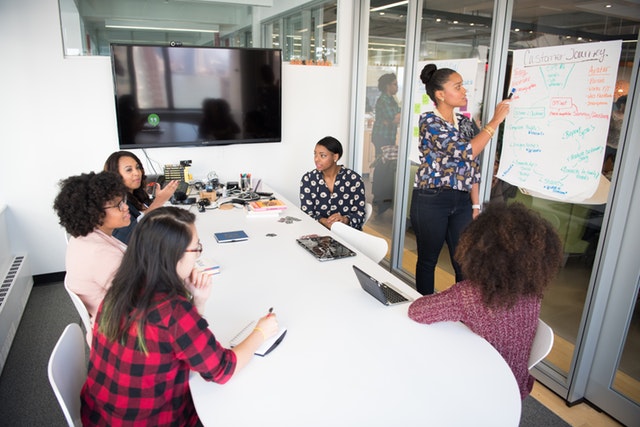 Six women in a meeting room having a discussion