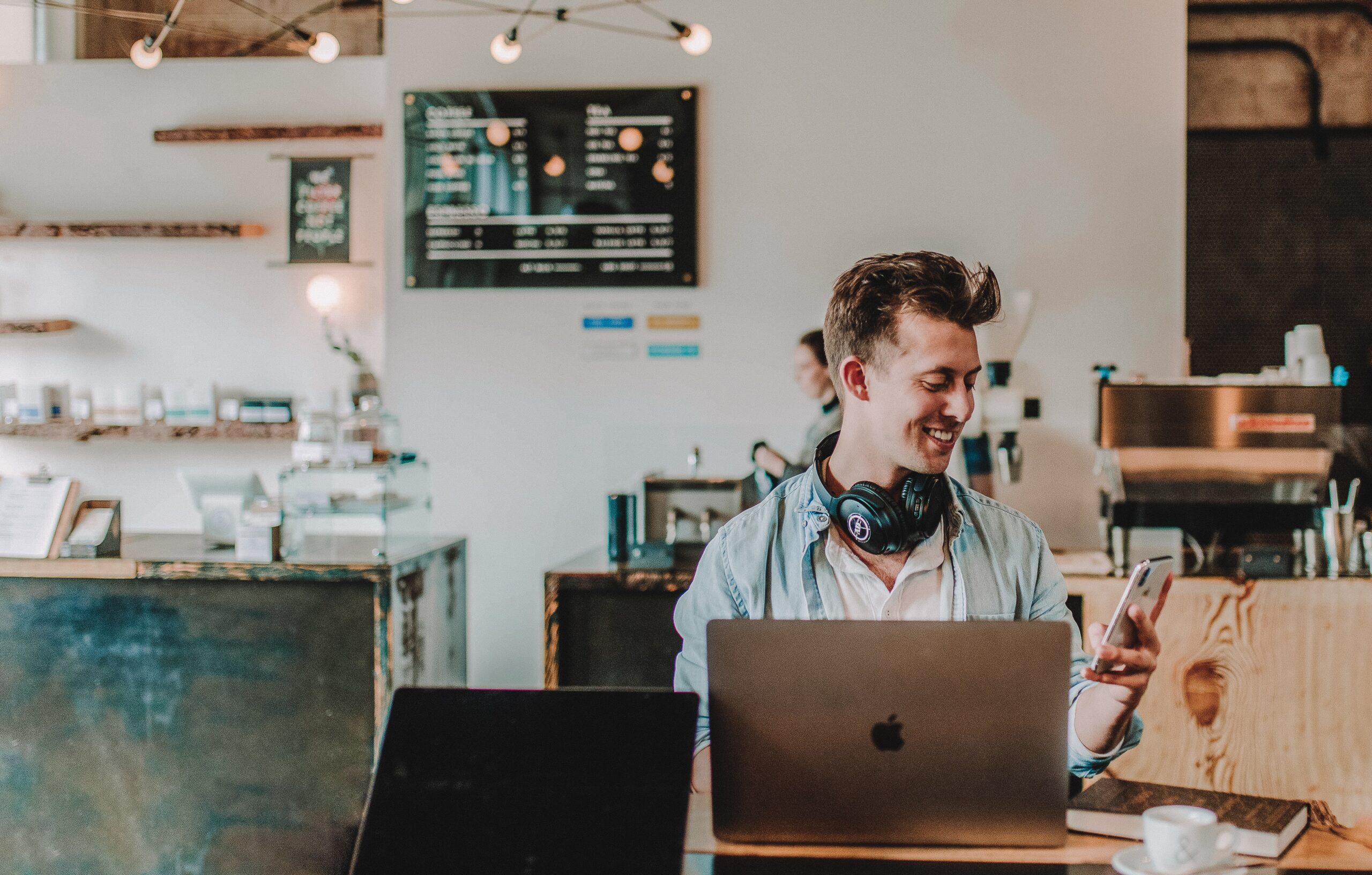 man in a cafe, holding his phone and smiling