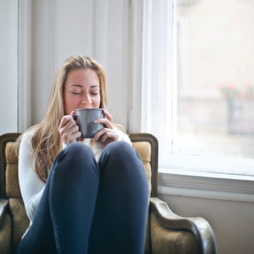woman sitting in a chair with her legs up and holding a cup in her hands